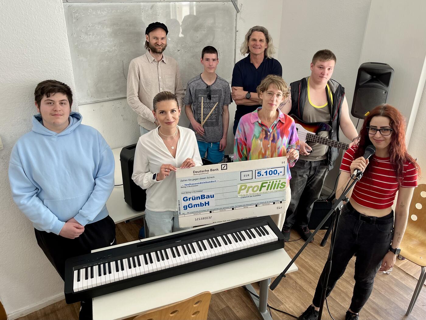v.l.n.r. hinten: David Bartelts (Musiklehrer), Thomas Schieferstein (Vorstand ProFiliis), v.l.n.r. vorne: Svenja Felbier (Projektbetreuung ProFiliis), Evi Austermann-Fasselt (Fundraising/Spenden GrünBau) sowie Teilnehmer:innen des Projekts. (Foto: Dietmar Wäsche (Projektorganisator GrünBau))