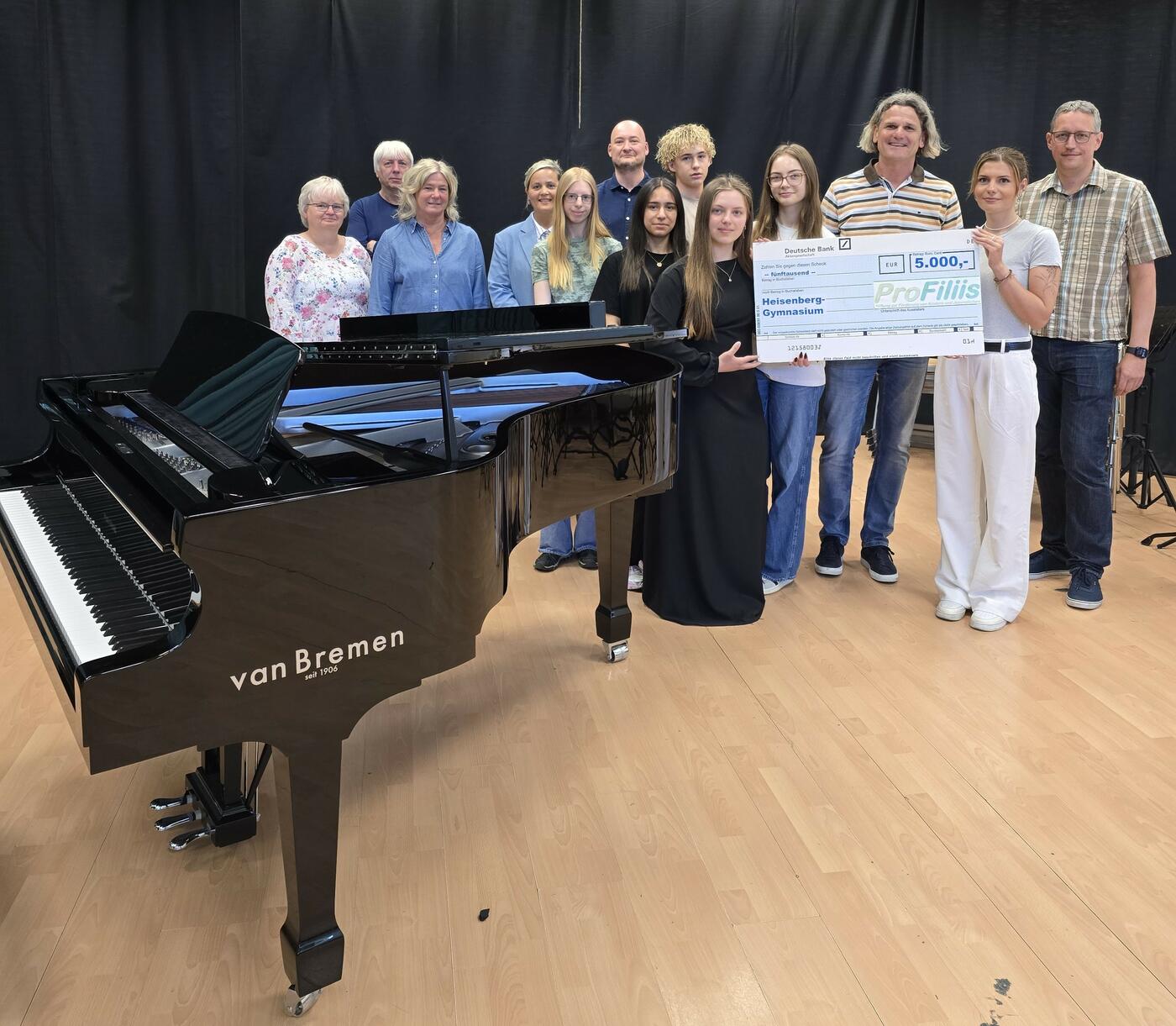 v.l.n.r.: Mechthild Rohpeter (Förderverein), Martin Knust (Musiklehrer), Andrea Aufmkolk (Musiklehrerin), Lisa Hidajat (Musiklehrerin), Turan Gizbili (Lehrer und Förderverein), Thomas Schieferstein (Vorstand ProFiliis), Svenja Felbier (Projektbetreuung ProFiliis), Torsten Averhaus (stellv. Schulleiter) sowie Schüler:innen des Heisenberg-Gymnasiums. (Foto: Katja Middeldorf (Schulleiterin)) 