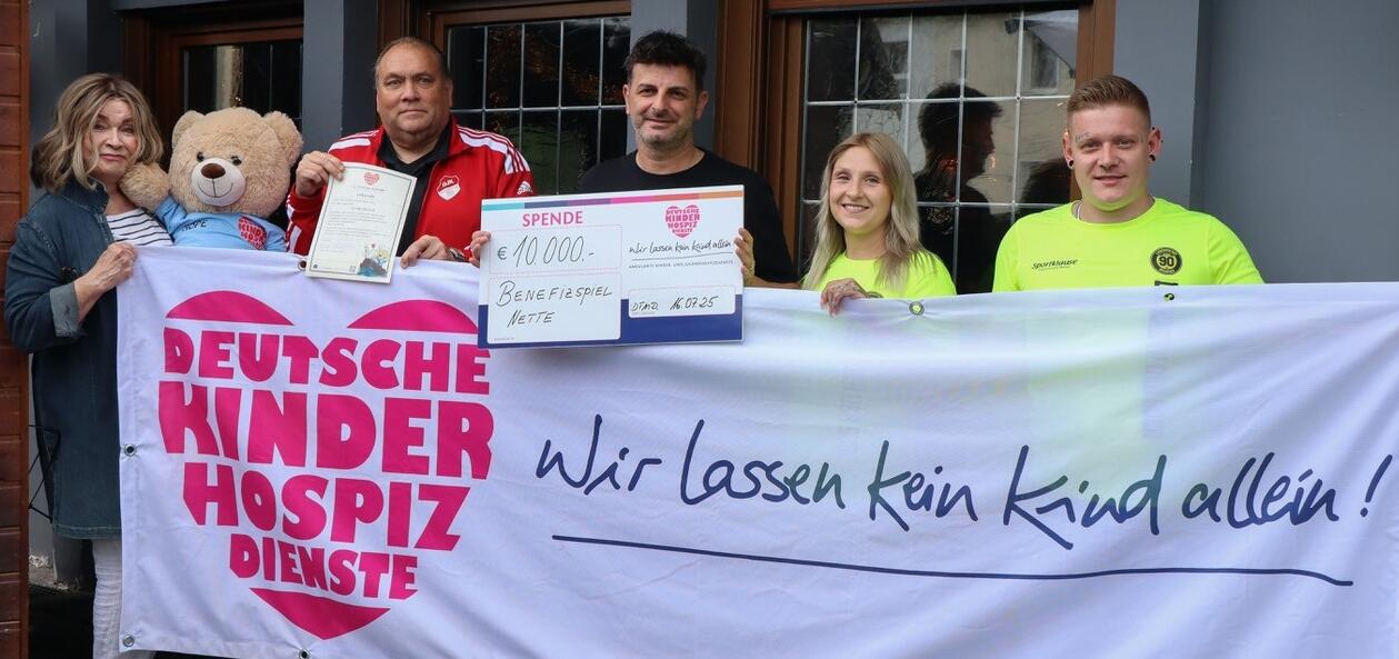 Überwältigt von der stolzen Summe, die am Ende für die Deutschen Kinderhospiz Dienste und damit  für die Begleitung von schwerstkranken Kinder in Dortmund und Umgebung zustande kam: Niko Savvidis, Initiator des großen Benefizspiels, Birgit Lindstedt sowie Bärenbotschafter Hope von den Deutschen Kinderhospiz Diensten und einige der Helfer, die dem Event zum Erfolg verholfen hatten. (Foto: Deutsche Kinderhospiz Dienste/ Simke Strobler)  
