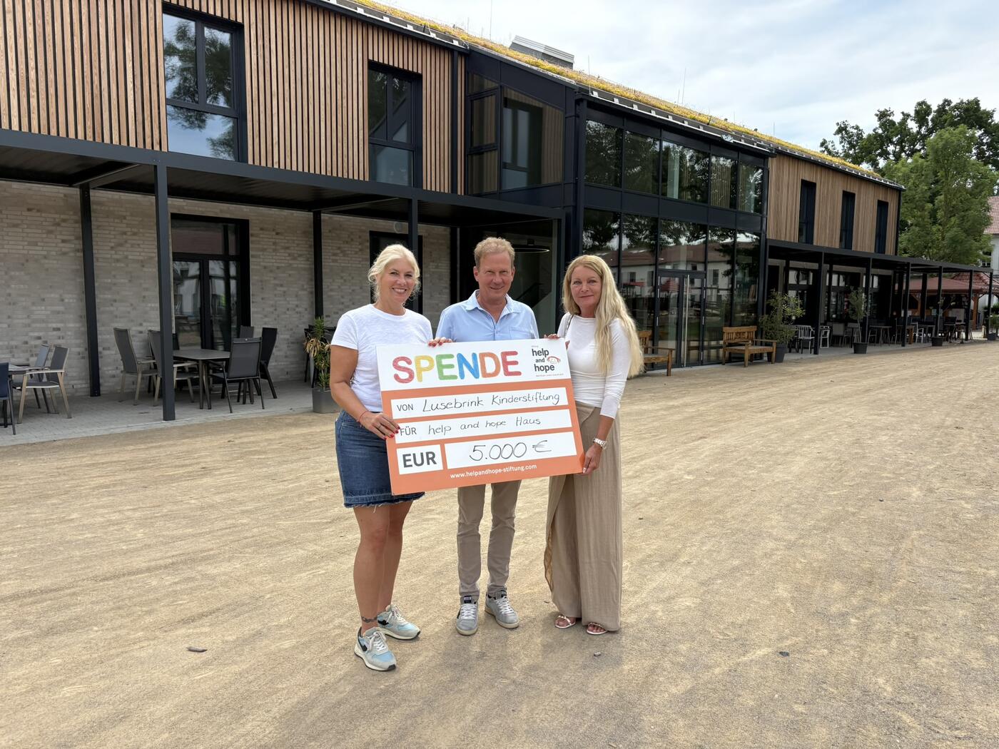  Vor dem neuen help and hope Haus überreichen Jörg (M.)  und Christiane (r.) Lusebrink die Spende der Lusebrink Kinderstiftung an  Sandra Heller, Vorstandsvorsitzende der help and hope Stiftung (l.). (Foto: help and hope Stiftung)
